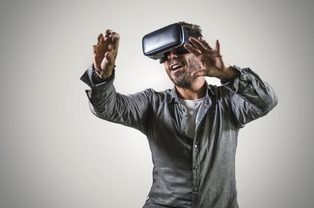 young happy and excited man wearing virtual reality VR goggles headset experimenting 3d illusion...