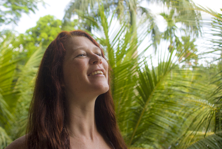 lifestyle fresh and natural portrait of young beautiful and happy red hair woman smiling cheerful and carefree enjoying Summer holidays trip in tropical island isolated on jungle backgroundの写真素材