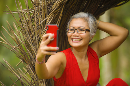 natural lifestyle portrait of attractive and happy middle aged 40s or 50s Asian woman with grey hair...