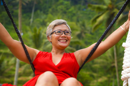 natural lifestyle portrait of attractive happy middle aged 40s - 50s Asian woman with grey hair and...