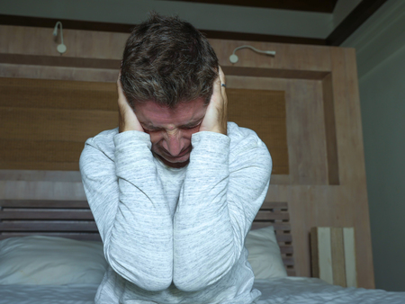 Despair. Dramatic portrait of middle aged man desperate and depressed crying at home bedroom feeling...