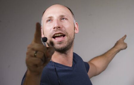 happy attractive and confident businessman speaker with headset giving coaching conference training for business success smiling cheerful and positive in casual code isolated on studio backgroundの写真素材
