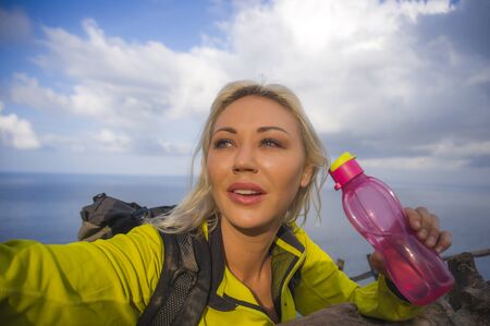 outdoors lifestyle portrait of young beautiful and happy hiker woman with backpack hiking on sea...
