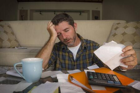 young attractive stressed and frustrated man at home living room couch doing domestic accounting...