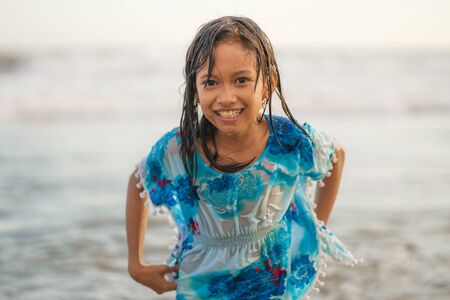 beach lifestyle portrait of young beautiful and happy 7 or 8 years old Asian American mixed child girl with wet hair enjoying holidays playing in the sea having fun with the water carefreeの写真素材