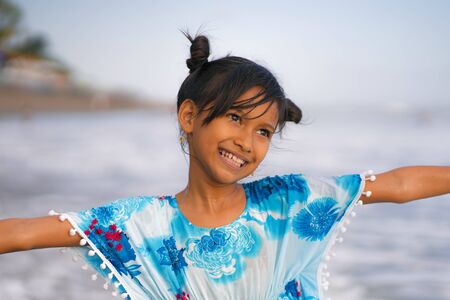 holiday beach lifestyle portrait of young beautiful and happy Asian child girl 8 or 9 years old with cute double buns hair style playing carefree in the sea enjoying Summer vacation having fun aloneの写真素材