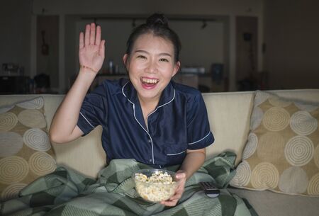 young beautiful happy and cheerful Asian Korean woman watching television comedy movie or hilarious...