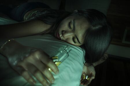 young beautiful desperate and wasted addict Asian Korean woman taking drug overdose lying on bed...