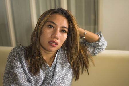 dramatic lifestyle portrait of young beautiful sad and depressed woman thoughtful and confused at...