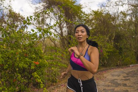 young attractive and exotic Asian Indonesian runner woman in jogging workout outdoors at countryside...