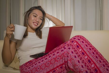 home lifestyle portrait of young attractive and natural Asian Indonesian woman in pajamas pants...