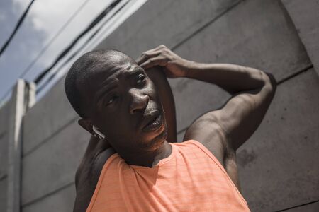 sport lifestyle portrait of young attractive and athletic black afro American man stretching arms and upper torso ready for running workout looking focused badass style in urban backgroundの写真素材
