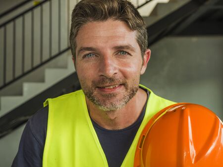 blue collar construction worker. Corporate portrait of young attractive and happy builder man or...