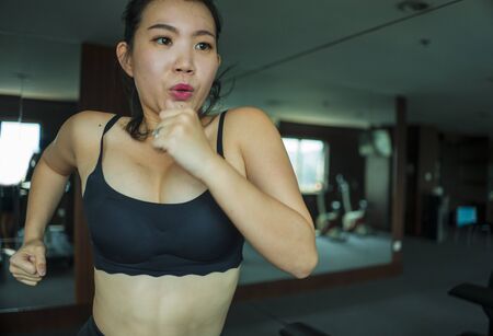 young attractive and fit Asian Chinese woman doing running workout at hotel gym or fitness club jogging in treadmill training hard in healthy lifestyle and body care conceptの写真素材