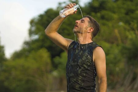 sport and fitness lifestyle portrait of young attractive and sweaty man pouring water on his face...