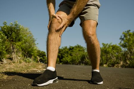 close up hands and legs of sport man injured touching his knee in pain suffering physical problem or...