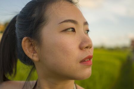 young happy and beautiful Asian woman enjoying nature at rice field. sweet Chinese girl in Summer dress at green field exploring countryside during holiday travel in wanderlust and tourismの写真素材