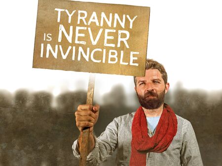 conceptual portrait of attractive hipster with scarf and beard protesting at political demonstration holding billboard with the message tyranny is never invincible defending human rights の写真素材
