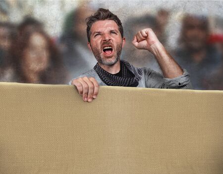 attractive and upset political activist man protesting in street march screaming holding blank copy...