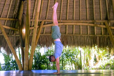 young attractive and happy man doing yoga drill and handstand balance exercise relaxed in harmony at...
