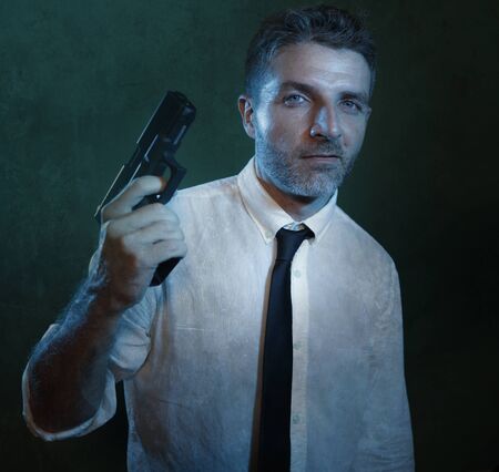 Man holding handgun - dramatic action portrait of attractive special agent or police officer aiming...