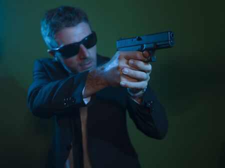 Man pointing handgun - dramatic action portrait of attractive special agent or police officer aiming...