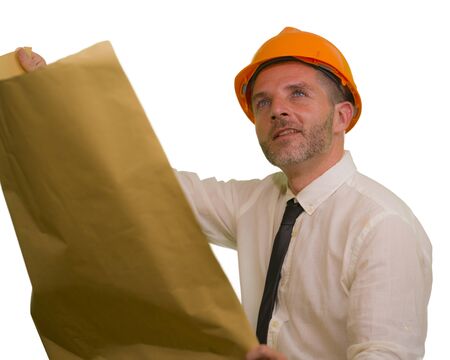 corporate portrait of attractive and successful industrial engineer or contractor man in working hardhat holding blueprint satisfied isolated on white background in construction businessの写真素材