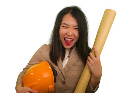 portrait of beautiful and happy Asian Chinese woman with hardhat holding building blueprints as architect engineer or constructor supervisor in businesswoman industry career successの写真素材