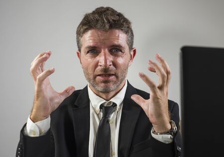 corporate business company worker in stress - attractive sad and depressed businessman working overwhelmed and desperate at office computer desk in financial executive job problems conceptの写真素材