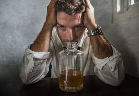 dramatic portrait of 30s to 40s drunk man in lose necktie drinking alcohol desperate and wasted in...