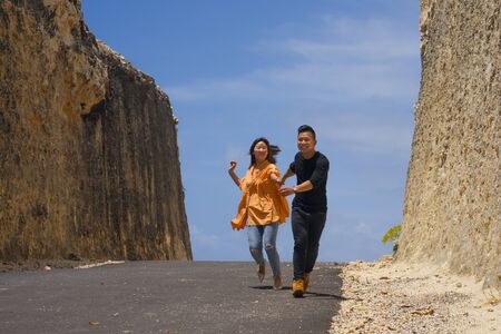 young happy and beautiful Asian Chinese couple in love enjoying outdoors journey running playful in...