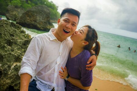 Summer holidays lifestyle portrait of young beautiful and sweet Asian Korean couple in love walking on the beach together enjoying honeymoon trip in the beach smiling cheerful and lovingの写真素材
