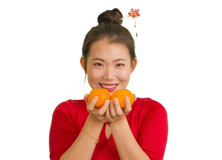 young beautiful and happy Asian woman in traditional Chinese New Year red dress holding orange fruit as symbol of prosperity isolated on white background in China culture tradition conceptの写真素材