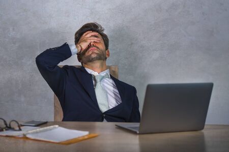 depressed and stressed attractive hispanic businessman in suit and tie working  exhausted at office...