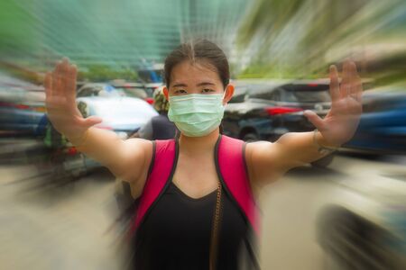 young beautiful and attractive Asian Chinese student woman walking on city street wearing protective...