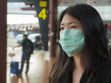 young beautiful and attractive Asian student at airport wearing protective facial mask against...