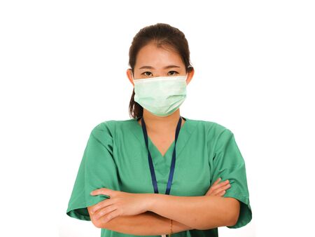 young beautiful and confident Asian Korean medicine doctor woman or hospital nurse in green scrubs and surgical protective face mask in protection against virus outbreak conceptの写真素材
