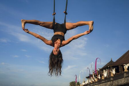 aero yoga workout - young attractive and athletic woman practicing aerial yoga exercise training...