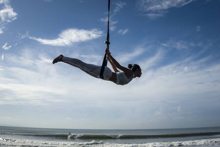 silhouette of young happy and athletic Asian Indonesian woman doing aero yoga workout training body...