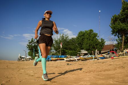 outdoors fitness lifestyle portrait of young attractive and athletic woman in compression running...