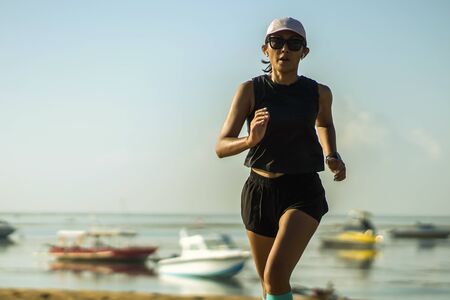 outdoors fitness lifestyle portrait of young attractive and athletic woman in compression running...