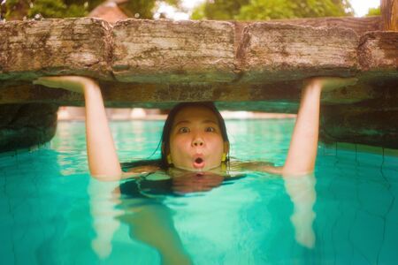 holidays lifestyle portrait of young beautiful and happy Asian Korean woman in bikini enjoying vacation trip relaxed and blissful at tropical resort swimming pool in exotic tourism and wanderlust conceptの写真素材