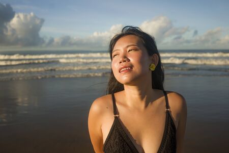 natural lifestyle portrait of young attractive and happy Asian Chinese woman in swimsuit walking on beautiful beach paradise feeling relaxed and cheerful enjoying holidays carefreeの写真素材