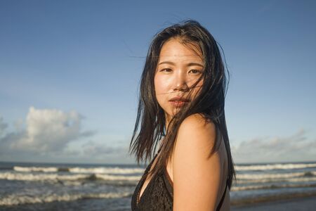 young attractive and cool Asian Korean woman in swimsuit walking on beautiful beach paradise feeling relaxed enjoying holidays in exotic travel destinationの写真素材