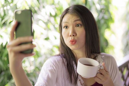 outdoors holiday lifestyle portrait of young beautiful and happy Asian Korean woman having morning...