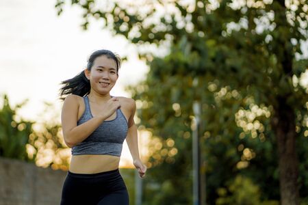 outdoors running workout - young happy and dedicated Asian Korean woman jogging at beautiful city...