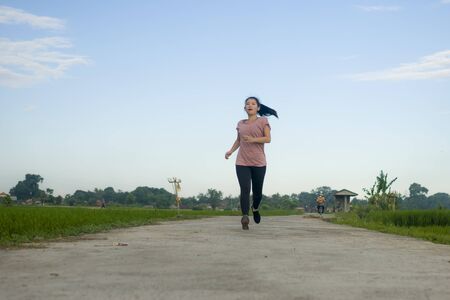outdoors jogging workout - young happy and dedicated Asian Korean woman running at beautiful...