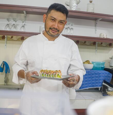 lifestyle portrait of Asian home cook man or professional chef cooking in clean kitchen showing...