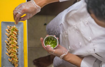 hands in gloves of Asian professional chef preparing delicious and healthy Japanese sushi rolls at restaurant kitchen working with beautiful ingredients making traditional Japan foodの写真素材