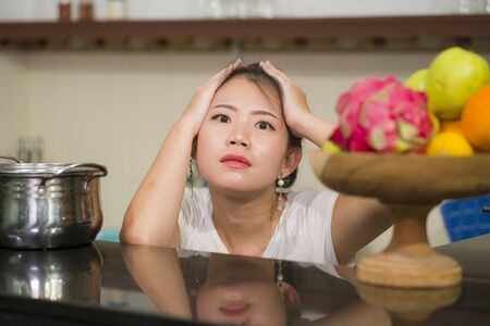 young frustrated Asian woman in domestic chores stress - lifestyle home portrait of beautiful...